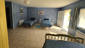 Een kamer met twee bedden, een radiator, een plafondventilator en een raam met gordijnen.