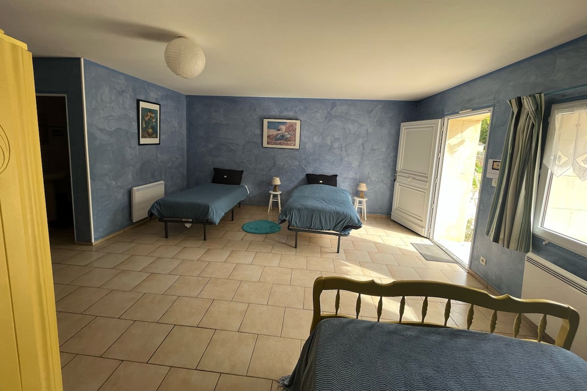Une chambre avec deux lits, un radiateur, un ventilateur de plafond et une fenêtre avec des rideaux.