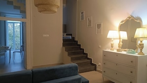 Una sala moderna con un sofá azul, una escalera, un área de comedor y un aparador con lámparas.