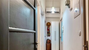 Un pasillo con piso de madera, una puerta oscura y un accesorio de iluminación.