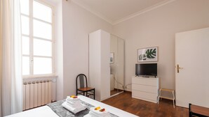 Une chambre d’hôtel avec un lit, une télévision, un petit bureau et une chaise.