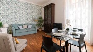 Un salon comprenant un canapé, une table à manger dressée pour quatre personnes et un grand meuble.