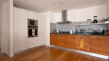 A modern kitchen with wooden cabinets, a built-in oven, and a stainless steel range hood.
