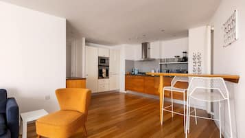 A modern kitchen with a central island, wooden cabinets, and a white chair.