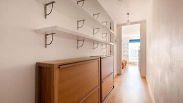 A hallway with wooden cabinets and metal hooks on the wall.