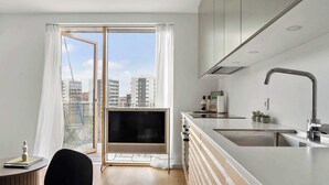 Une cuisine moderne dotée d’une grande fenêtre, d’un téléviseur à écran plat et d’un évier.