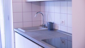 Une cuisine moderne avec un évier en acier inoxydable, un porte-gobelet bleu et des armoires blanches.