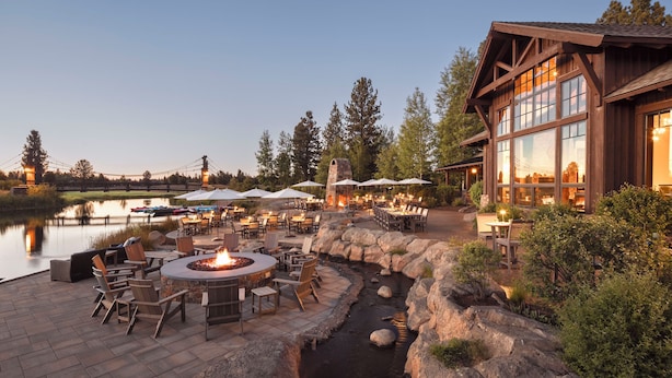 An outdoor patio area with a fire pit, seating, and a view of a lake. - Modern Caldera Home with Access to Forest House (Bend)
