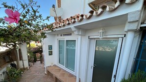 Un edificio con techo de tejas, una puerta con panel de vidrio y un banco en el exterior.