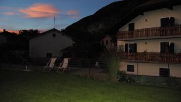 Ein zweistöckiges Gebäude mit Balkon, umzäunter Garten und einem Stuhl.