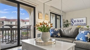 Een moderne woonkamer met uitzicht op een woongebied, een balkon en een bord met Salty Beach Vacation Rentals.