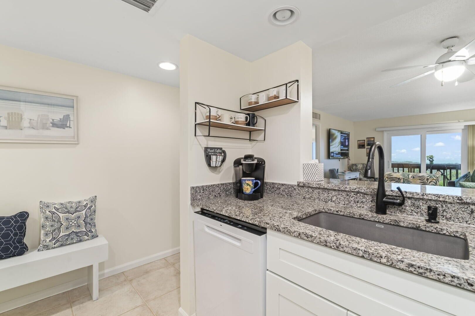 A modern kitchen with granite countertops, a coffee maker, and a built-in dishwasher.