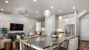 A modern kitchen with a central island, white cabinetry, stainless steel appliances, and pendant lighting. - Grand Slam Getaway #5 5 Bedroom Townhouse (Santa Clara)