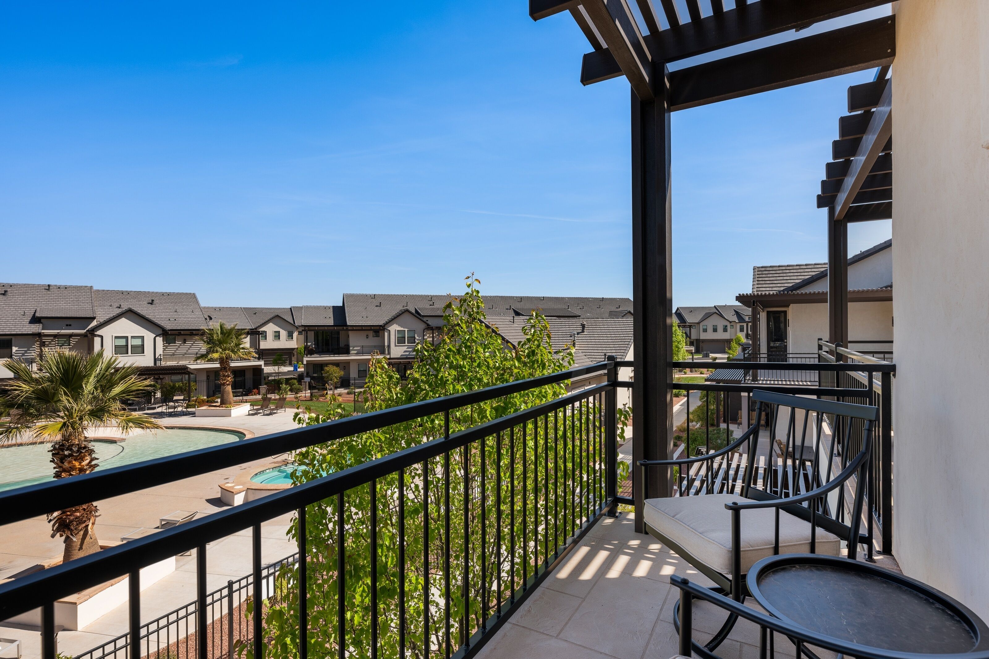 A balcony with a pool, outdoor seating, and a view of neighboring buildings.