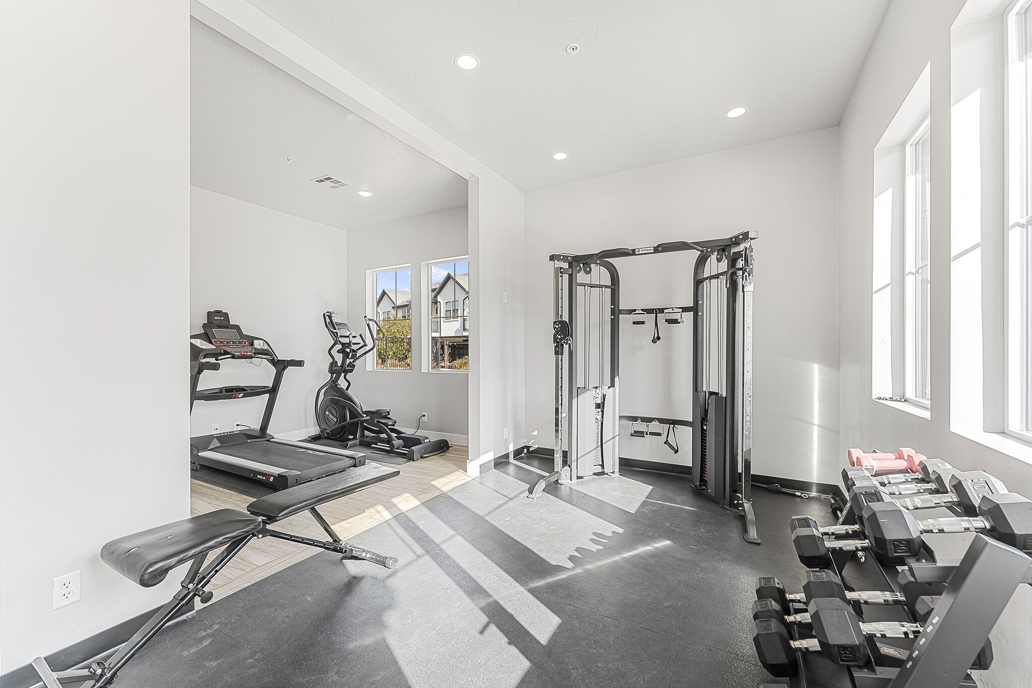 A gym with treadmills, weight machines, and dumbbells.