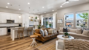 A modern kitchen with white cabinets, a microwave, and a dining area with a brown leather couch and wooden chairs. - Grand Slam Getaway #5 5 Bedroom Townhouse (Santa Clara)