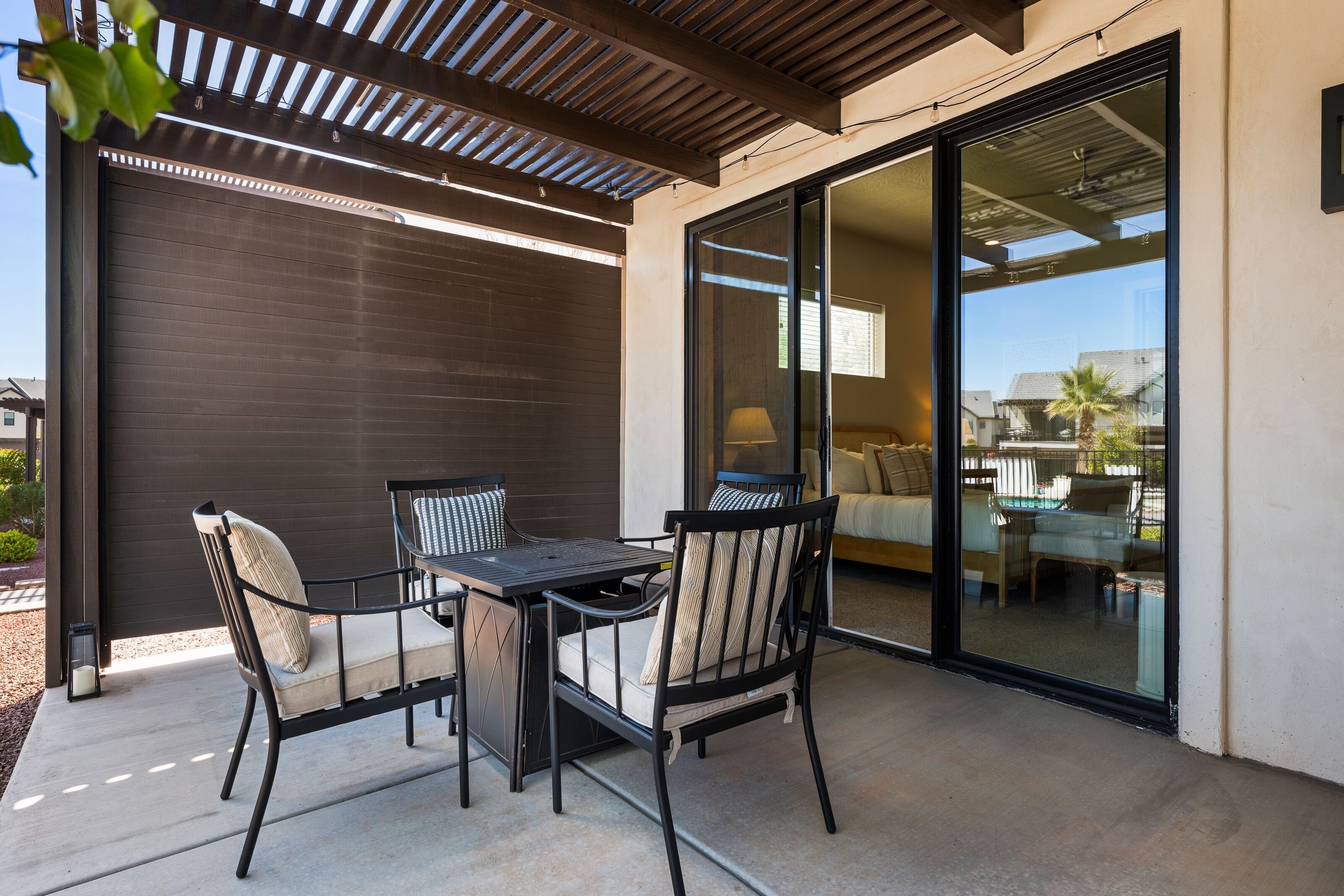 An outdoor patio with a table and chairs, a sliding glass door leading to an interior space, and a pergola overhead.