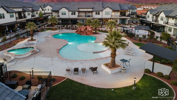 A resort with a large pool, multiple buildings, and a mountainous backdrop. - Grand Slam Getaway #5 5 Bedroom Townhouse (Santa Clara)