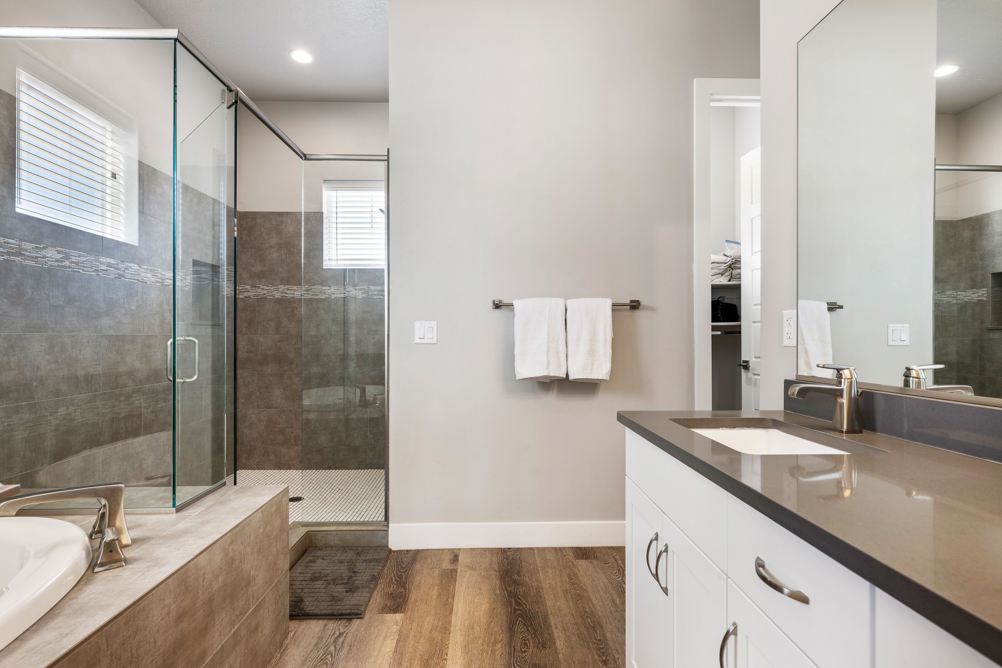 A modern bathroom with a glass-enclosed shower, a large mirror, and a vanity with a sink and countertop.