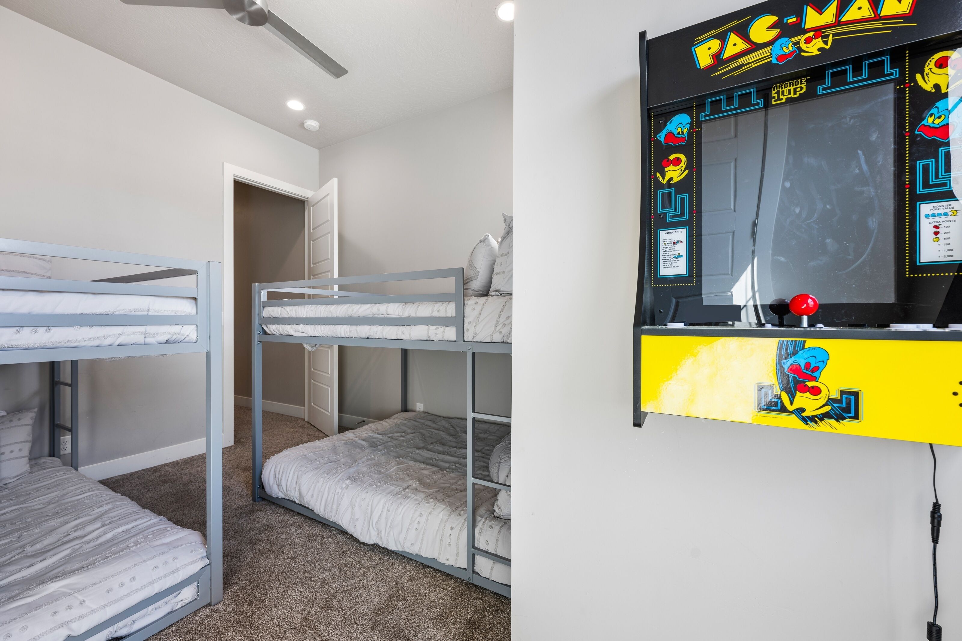 A bunk bed room with a Pac-Man arcade machine.
