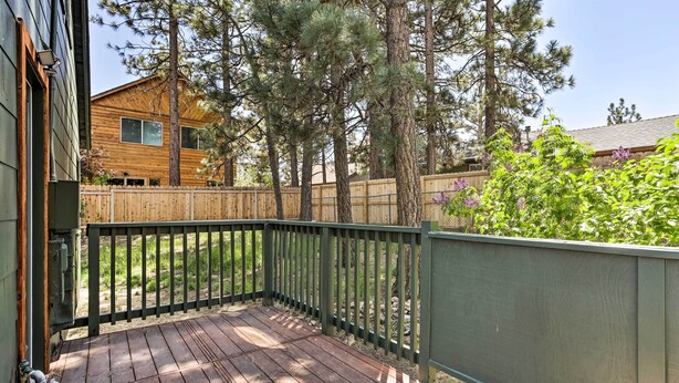 A wooden deck with a green fence, surrounded by trees and a wooden fence. - Modern Big Bear Lake Cabin w/ Lake Access! (Big Bear Lake)