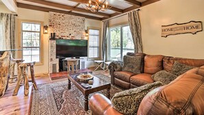 A cozy living room with a fireplace, leather sofa, and a television. - Modern Big Bear Lake Cabin w/ Lake Access! (Big Bear Lake)