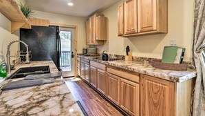 A kitchen with wooden cabinets, a marble countertop, and a stainless steel sink. - Modern Big Bear Lake Cabin w/ Lake Access! (Big Bear Lake)
