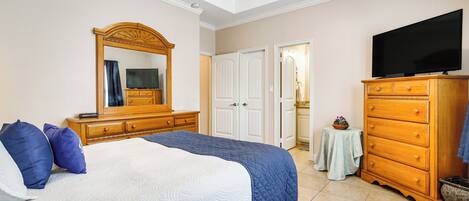 A bedroom with a bed, dresser, television, and a mirror.