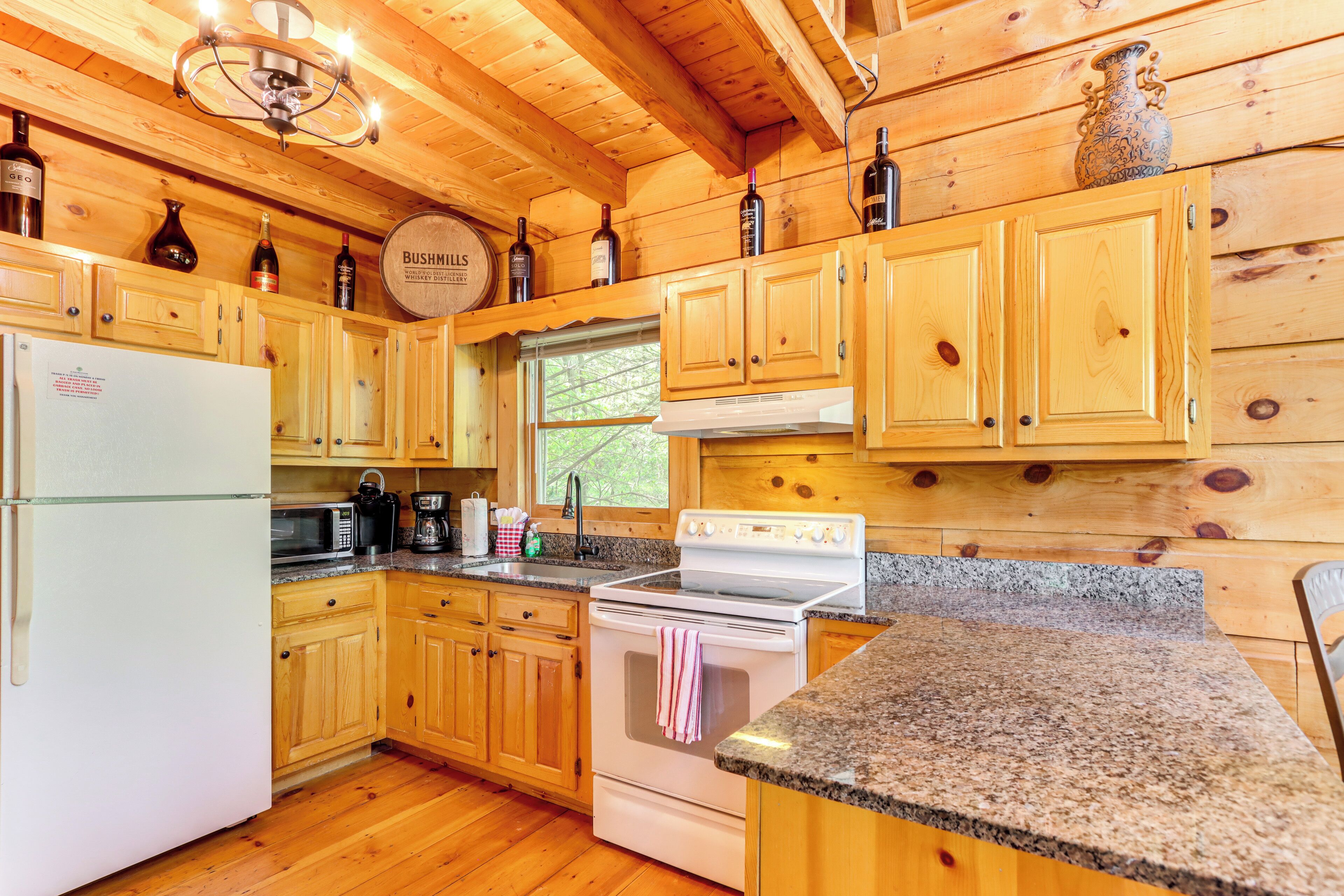 A wooden cabin kitchen with a refrigerator, stove, microwave, and wooden cabinets.