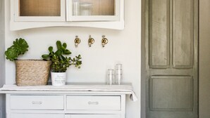 Una cocina con armarios blancos, una lámpara colgante y una puerta al fondo.