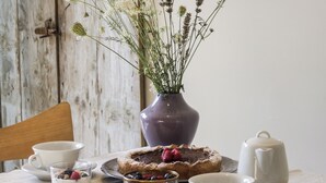 Una mesa de madera rústica con un florero, un plato de pasteles y una tetera.