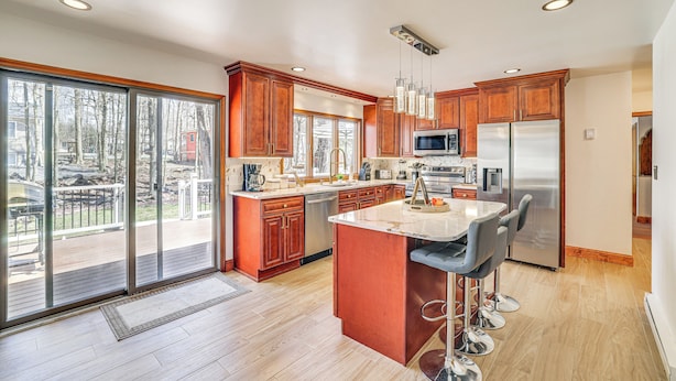 A modern kitchen with a large island, stainless steel appliances, and sliding glass doors leading to a deck. - Spacious Retreat 7 Mi to Tobyhanna State Park! (Tobyhanna)