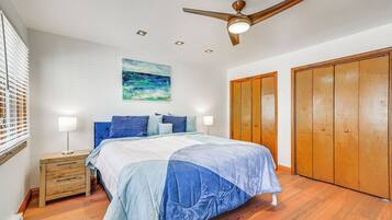 Ein Schlafzimmer mit Bett, Nachttisch, Deckenventilator und Kleiderschrank.