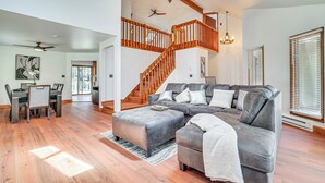 A spacious living room with a large gray sectional sofa, a wooden staircase, and a dining area with a gray table and chairs. - Spacious Retreat 7 Mi to Tobyhanna State Park! (Tobyhanna)