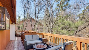A wooden deck with wicker furniture and a fire pit. - 8 Mi to Big Bear Lake: Cabin w/ Deck & Fireplace (Sugarloaf)
