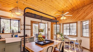 A wooden interior with a kitchen, dining area, and large windows. - 8 Mi to Big Bear Lake: Cabin w/ Deck & Fireplace (Sugarloaf)