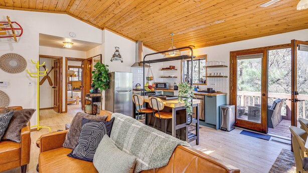 A cozy living room with a wooden ceiling, a dining area, and a kitchen with a view of the outdoors. - 8 Mi to Big Bear Lake: Cabin w/ Deck & Fireplace (Sugarloaf)