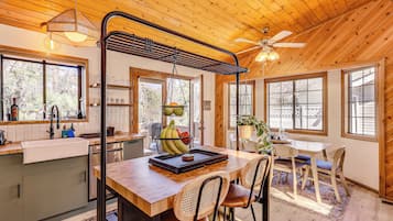 Un interior de madera con cocina, comedor y ventanas amplias.