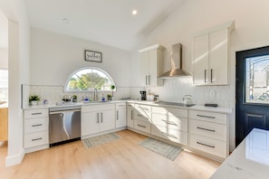 A modern kitchen with white cabinetry, a stainless steel dishwasher, a large window, and a black door. - Pet-friendly Lake Norman Retreat w/ Deck & Grill (Mooresville)