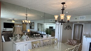 A dining area with a glass table, wooden chairs, and a chandelier. - 3 Master Suites all with Gulf Front View! Free Golf Daily! (Panama City Beach)