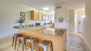 A kitchen with granite countertops, wooden cabinets, and stainless steel bar stools.