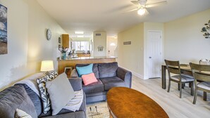 A living room with a gray sofa, a coffee table, and a dining area with wooden chairs and a table.