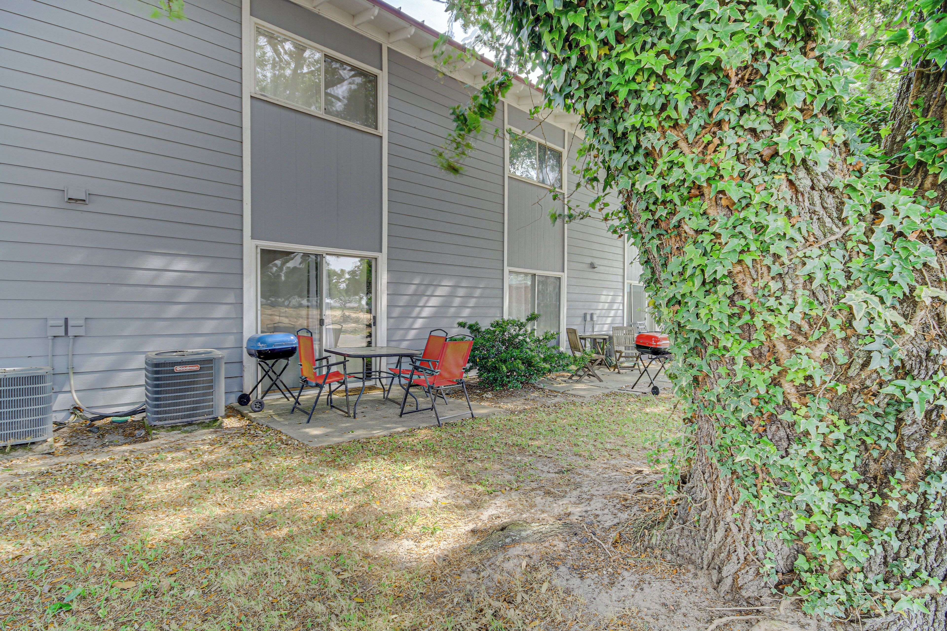 A patio area with outdoor furniture, air conditioning units, and a tree with ivy.