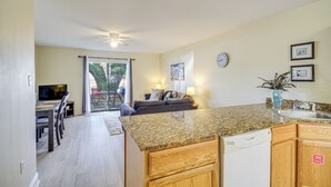A kitchen with granite countertops, wooden cabinets, a dishwasher, and a dining area with a table and chairs.