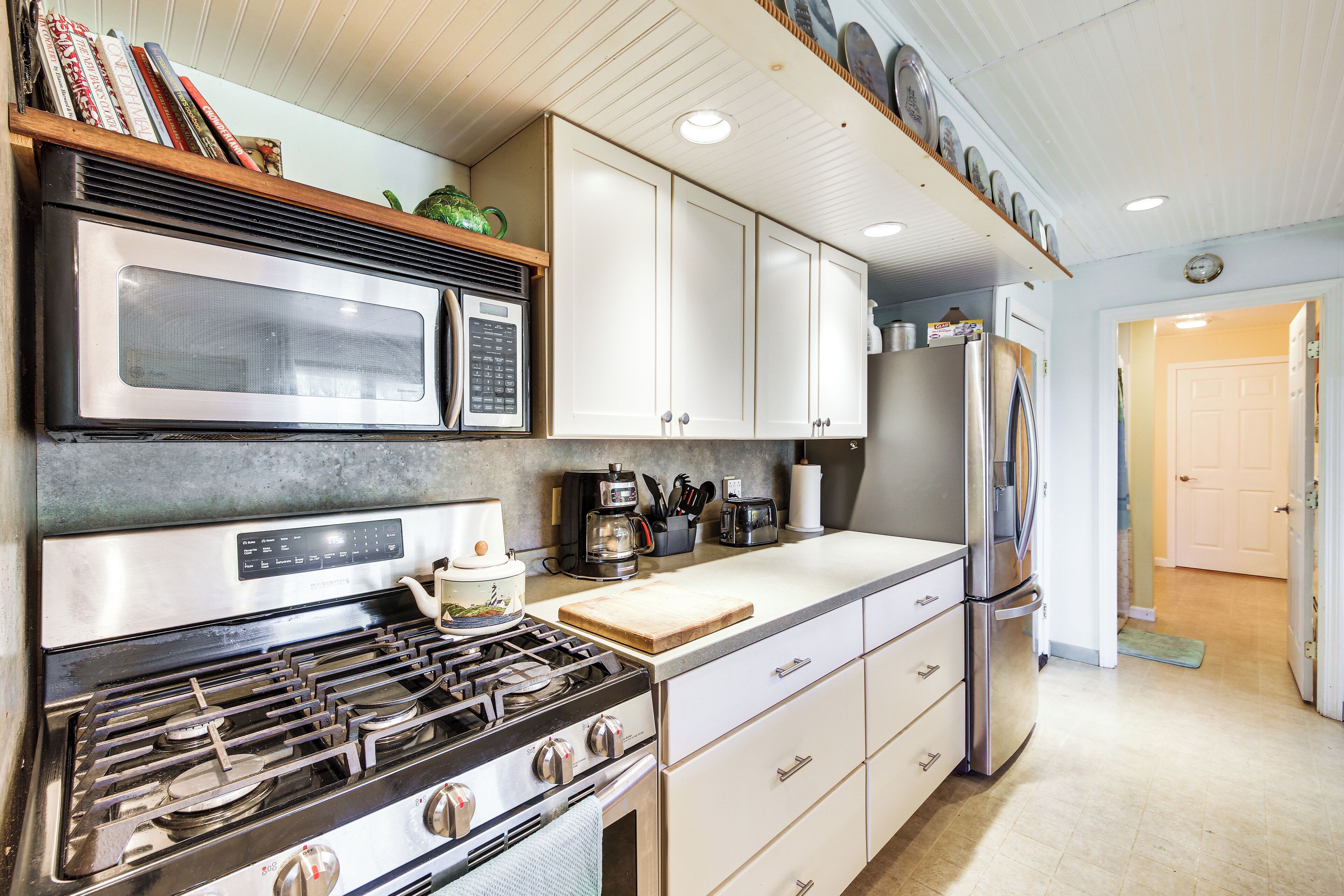 A kitchen with a stove, microwave, cabinets, and a refrigerator.