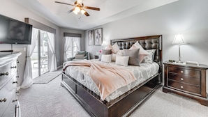 A bedroom with a large bed, a ceiling fan, a TV, and a nightstand with a lamp. - Near Golf & Wdw: Family-friendly Home in Davenport (Davenport)