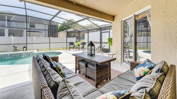A covered patio area with a pool, outdoor furniture, and a view of neighboring houses. - Near Golf & Wdw: Family-friendly Home in Davenport (Davenport)