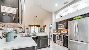 A modern kitchen with stainless steel appliances, a large island, and a decorative sign. - Near Golf & Wdw: Family-friendly Home in Davenport (Davenport)