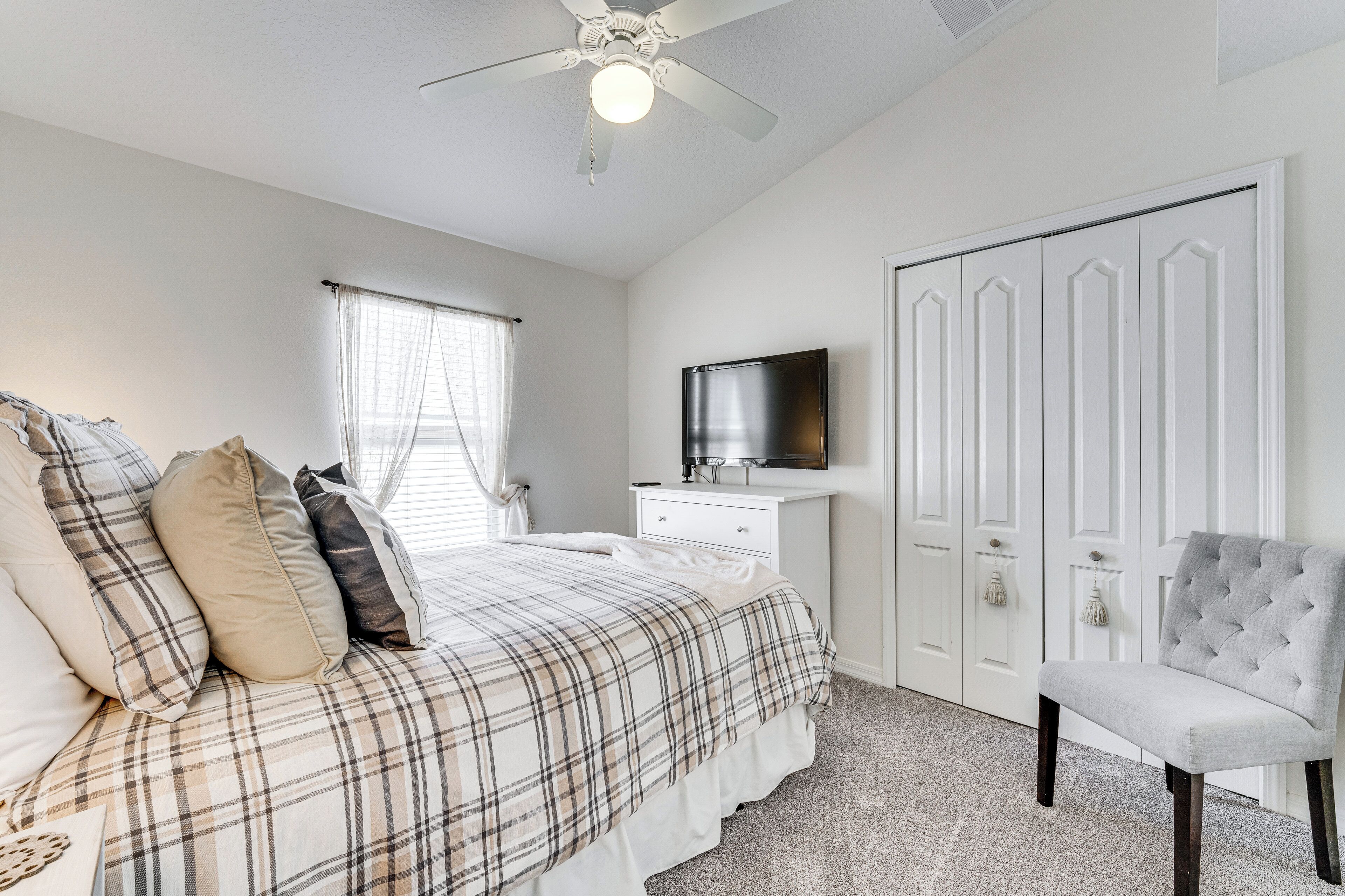 A bedroom with a bed, a chair, a TV, and a wardrobe.