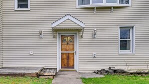 A house with a wooden front door, a small porch, and a stone step leading to the door. - Riverfront Baldwinsville Apartment w/ Shared Deck! (Baldwinsville)